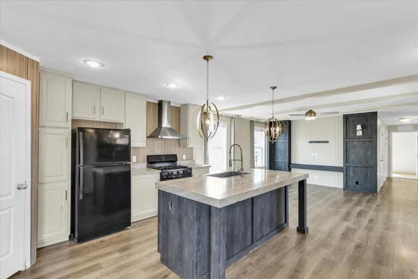 a kitchen with stainless steel appliances granite countertop a refrigerator a sink dishwasher a stove and a oven with wooden floor