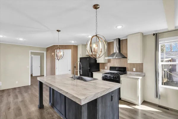 a kitchen with stainless steel appliances granite countertop a stove a refrigerator a kitchen island a sink dishwasher and white cabinets with wooden floor