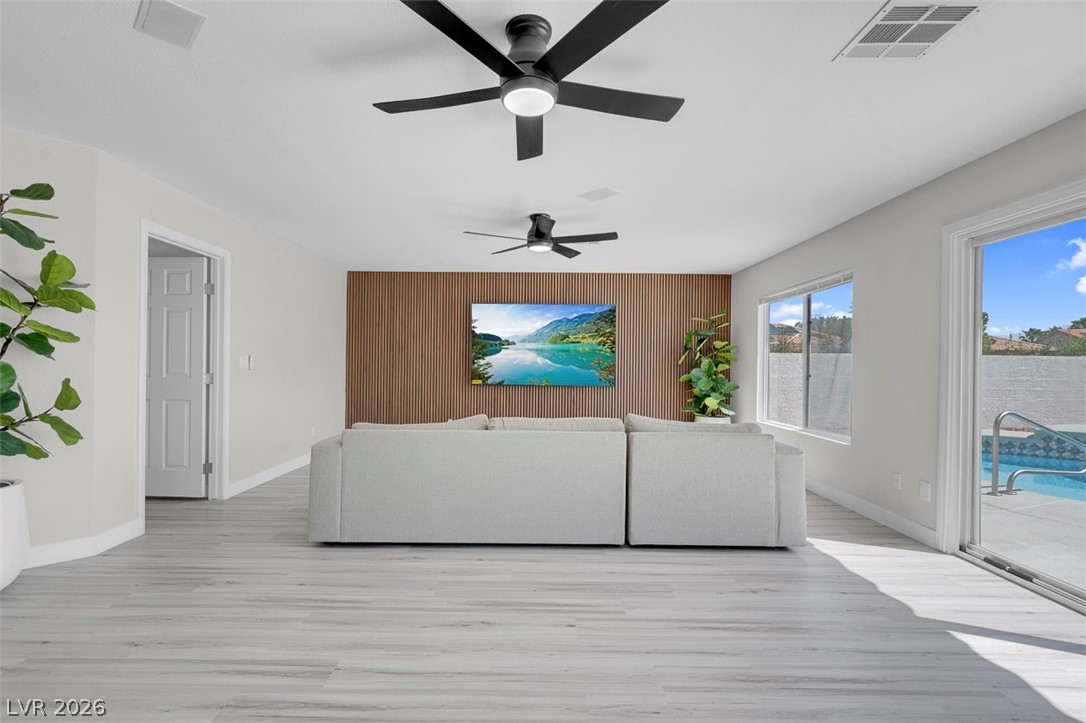 3604 North Campbell Road Las Vegas, NV 89129 - Photo 26 of 54 Living area with light wood-style flooring, baseboards, a ceiling fan, wood walls, and an accent wall