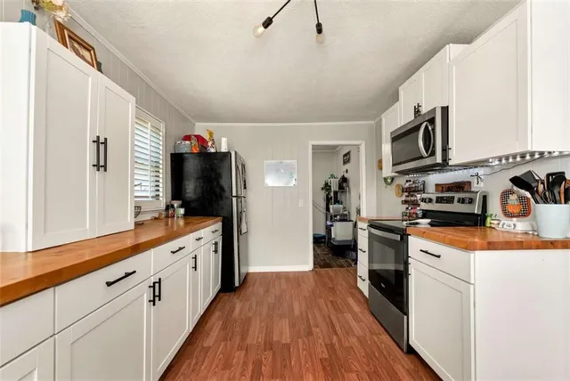 a kitchen with stainless steel appliances granite countertop a refrigerator a stove top oven a sink dishwasher and wooden cabinets with wooden floor