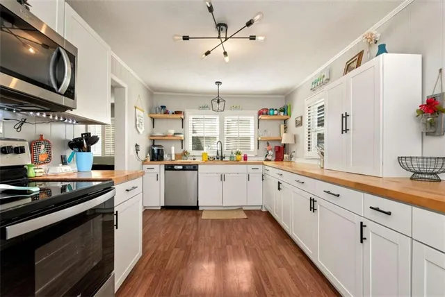 a kitchen with stainless steel appliances granite countertop wooden cabinets a sink a stove a refrigerator and island with wooden floor