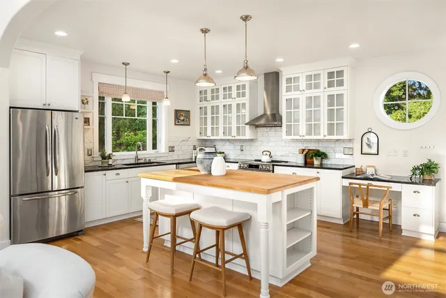 a kitchen with stainless steel appliances granite countertop a table chairs a sink and a refrigerator