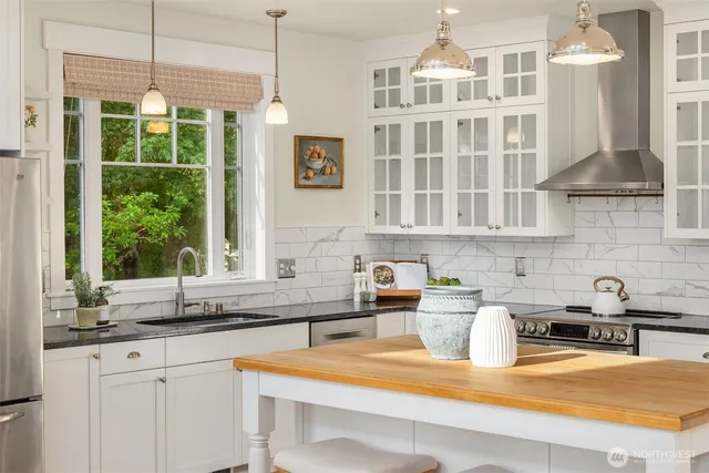 a kitchen with stainless steel appliances granite countertop a sink window and cabinets