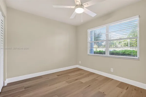 a view of an empty room with wooden floor and a window