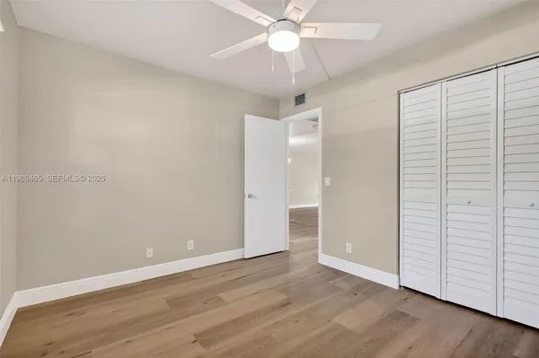 a view of an empty room with wooden floor and a ceiling fan