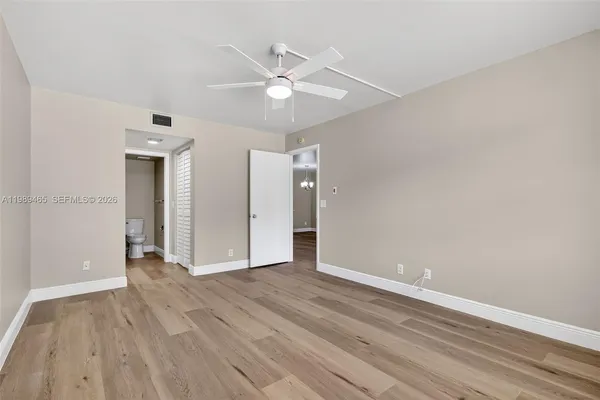a view of an empty room with wooden floor and a ceiling fan