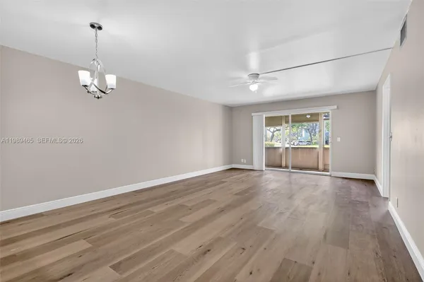 an empty room with wooden floor fan and windows