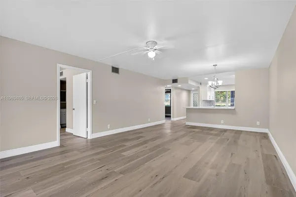 an empty room with wooden floor ceiling fan and windows