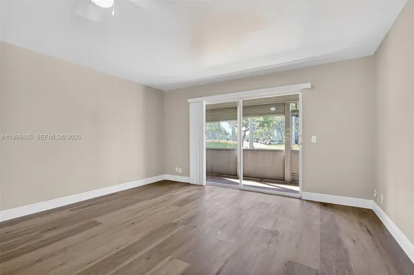 a view of an empty room with wooden floor and a window