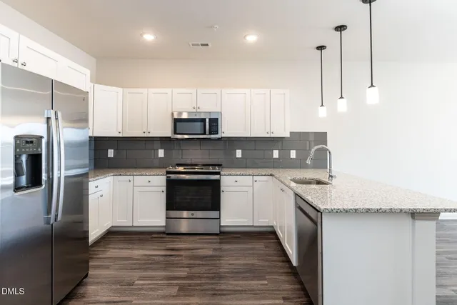 a kitchen with stainless steel appliances granite countertop a refrigerator a sink a stove a microwave and wooden cabinets