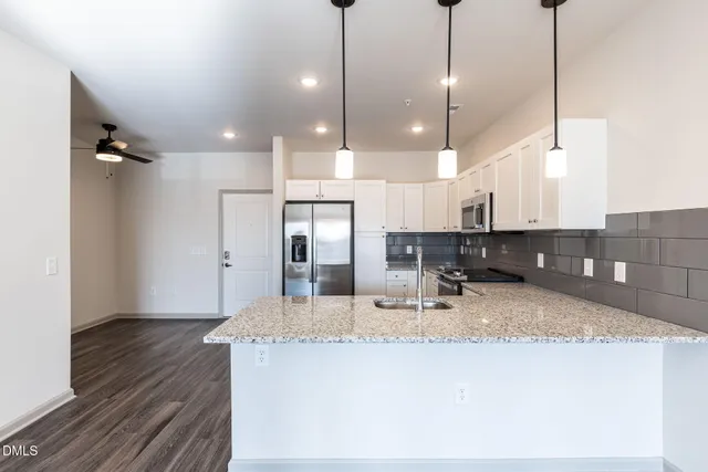 a kitchen with kitchen island a counter top space a sink appliances and cabinets