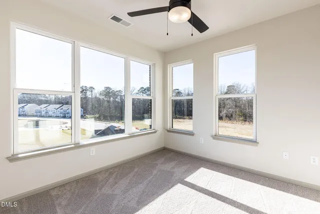 a view of an empty room with a window and a kitchen