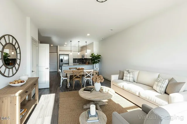 a living room with stainless steel appliances furniture a rug and a view of kitchen