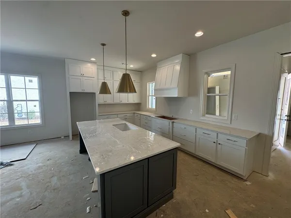 a kitchen with stainless steel appliances granite countertop a sink a stove a refrigerator and white cabinets