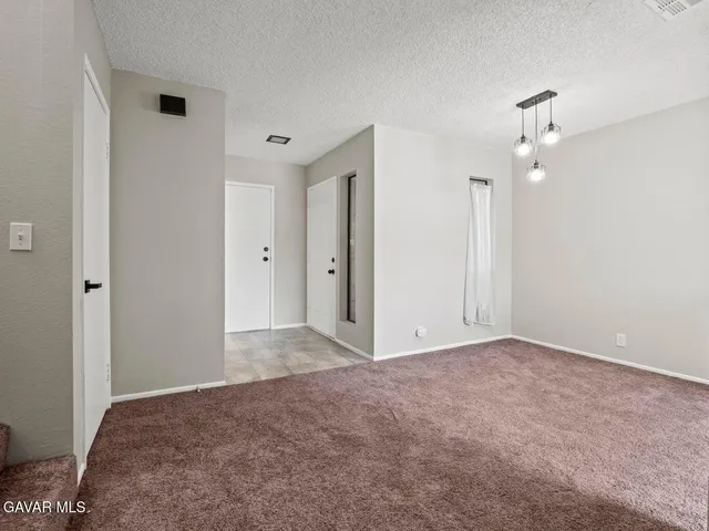 a view of a big room with chandelier fan and windows