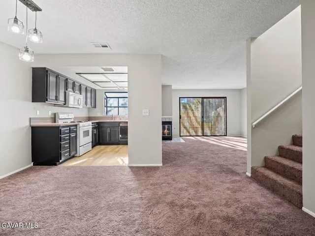 a view of a kitchen with stainless steel appliances granite countertop a stove and cabinets