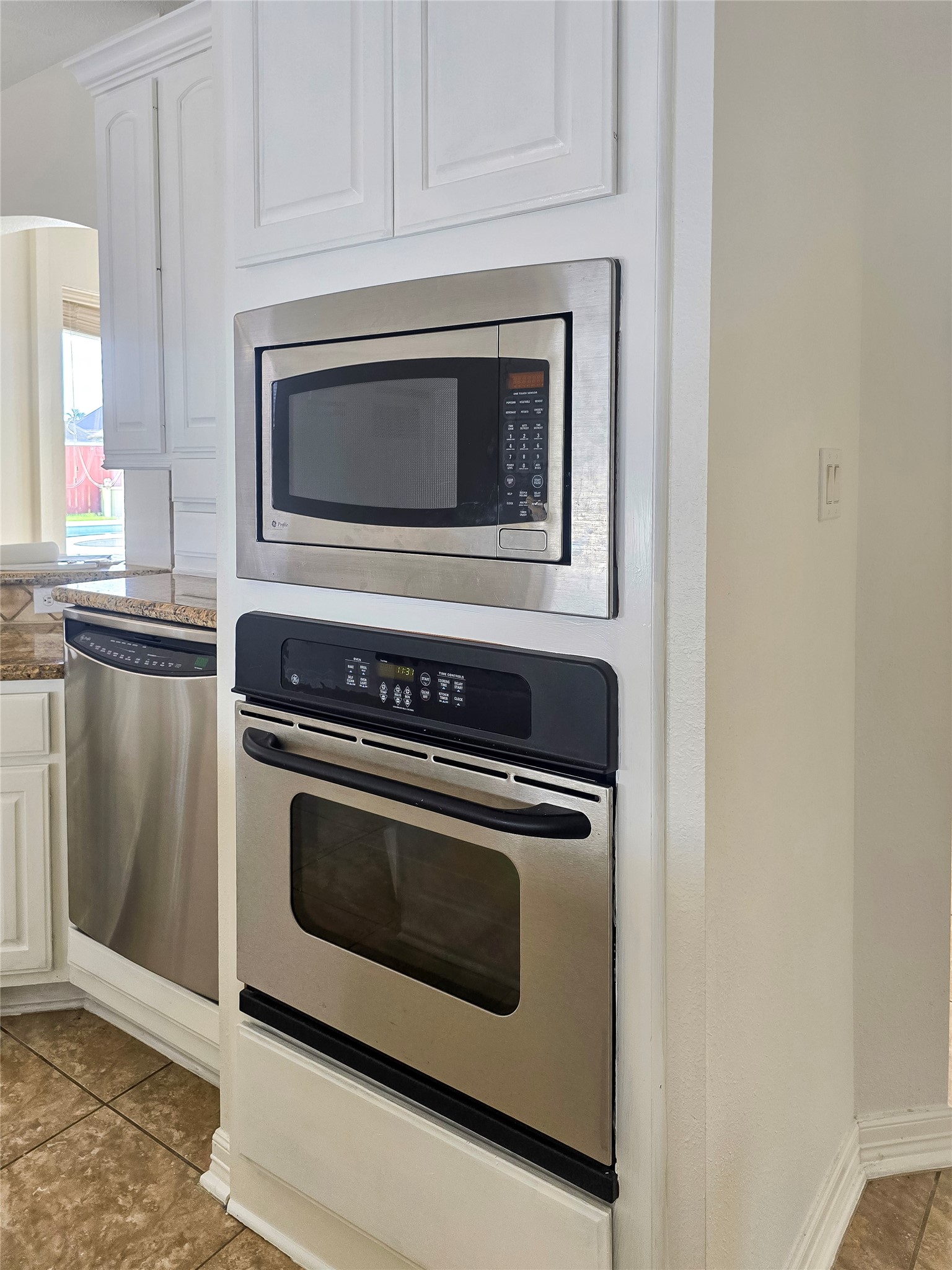 6506 Monte Bello Ridge Lane Houston, TX 77041 - Photo 7 of 39 This kitchen features built-in stainless steel appliances, including a microwave and oven, with adjacent cabinetry for storage, and a dishwasher, all complemented by tiled flooring and a granite countertop.