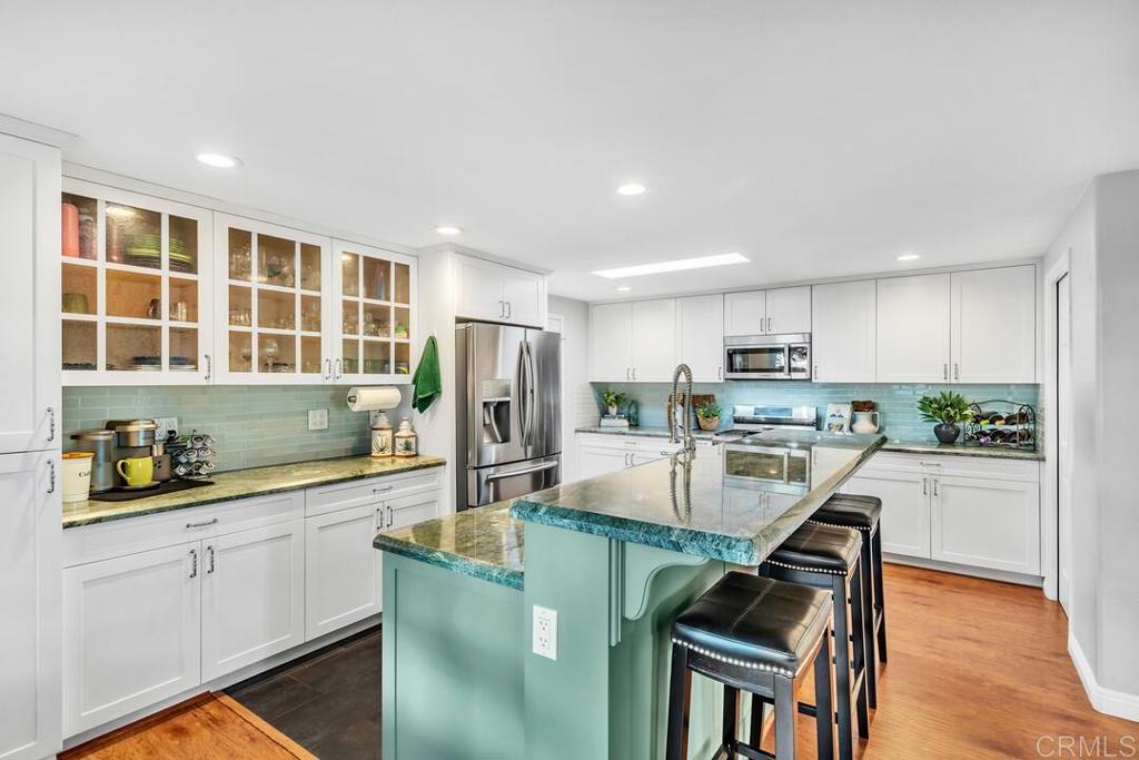 4169 Rhodes Way Oceanside, CA 92056 - Photo 14 of 42 a kitchen with stainless steel appliances a sink a stove a refrigerator cabinets and a dining table with wooden floor