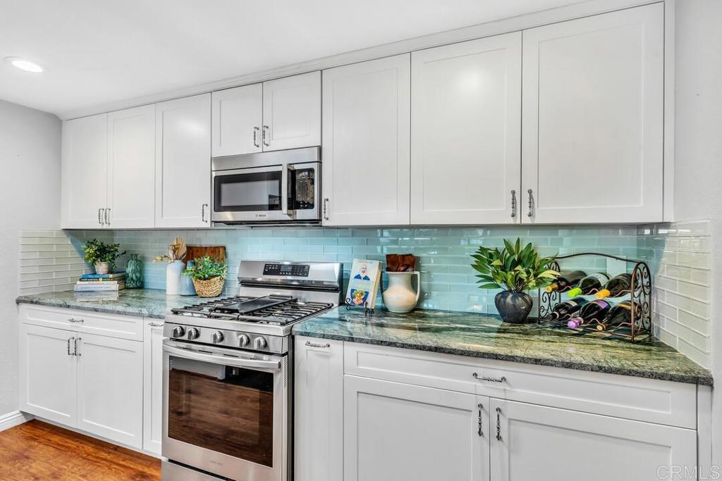 4169 Rhodes Way Oceanside, CA 92056 - Photo 15 of 42 a kitchen with stainless steel appliances granite countertop white cabinets a stove a sink and dishwasher
