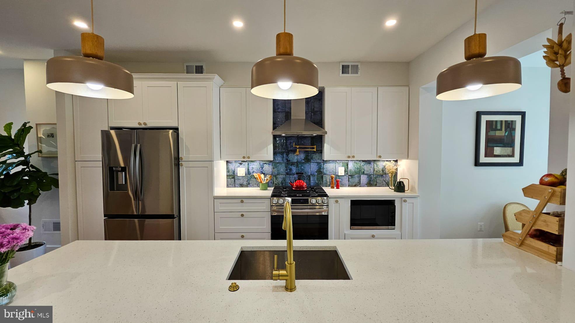 a kitchen with stainless steel appliances kitchen island granite countertop a refrigerator and a stove top oven