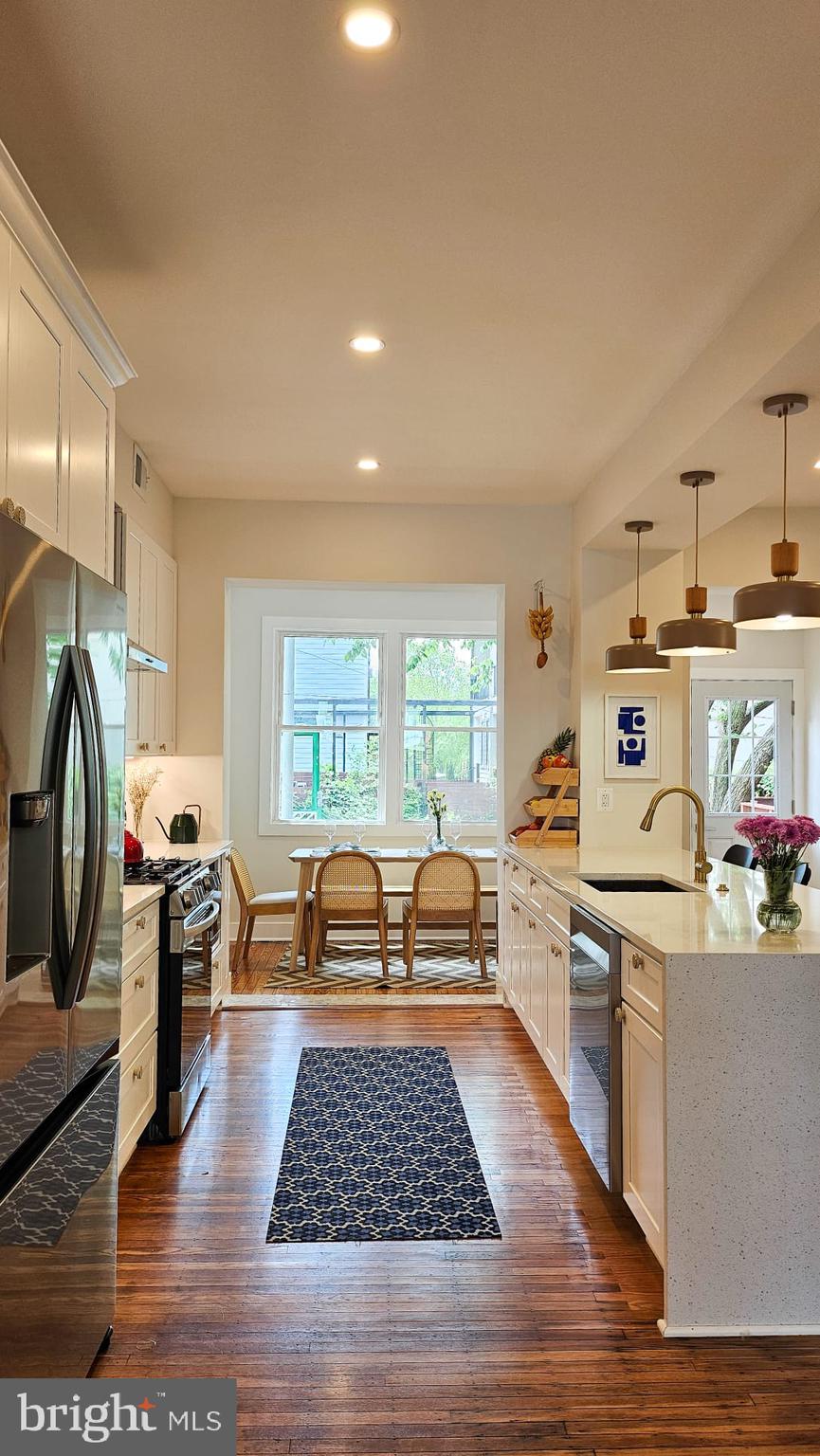 3206 Warder Street Northwest Washington, DC 20010 - Photo 6 of 30 a kitchen with stainless steel appliances granite countertop a stove top oven a sink a dining table and chairs with wooden floor