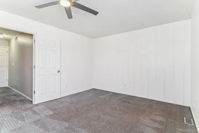 an empty room with a ceiling fan and carpet