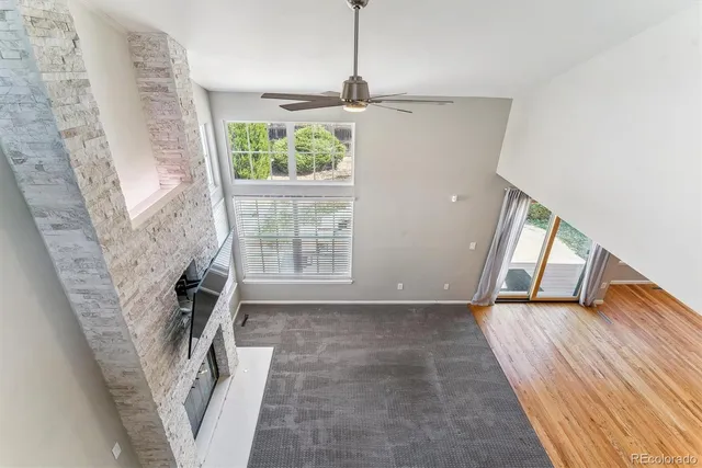a view of a hallway to a livingroom with wooden floor and a staircase