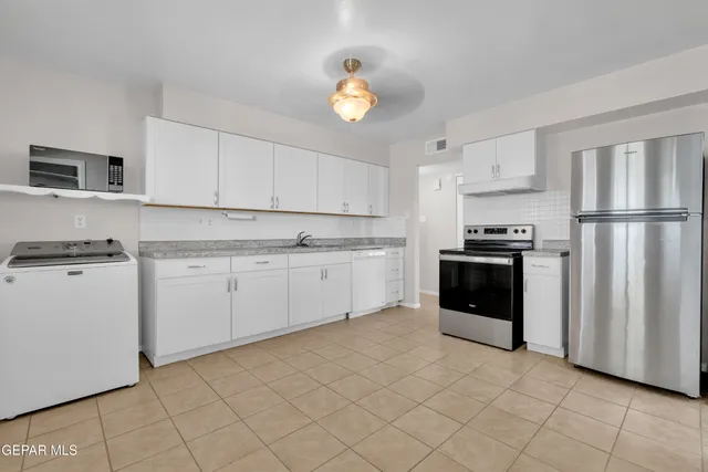 a kitchen with granite countertop white cabinets and stainless steel appliances