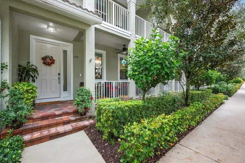 a view of a house with potted plants and a large tree