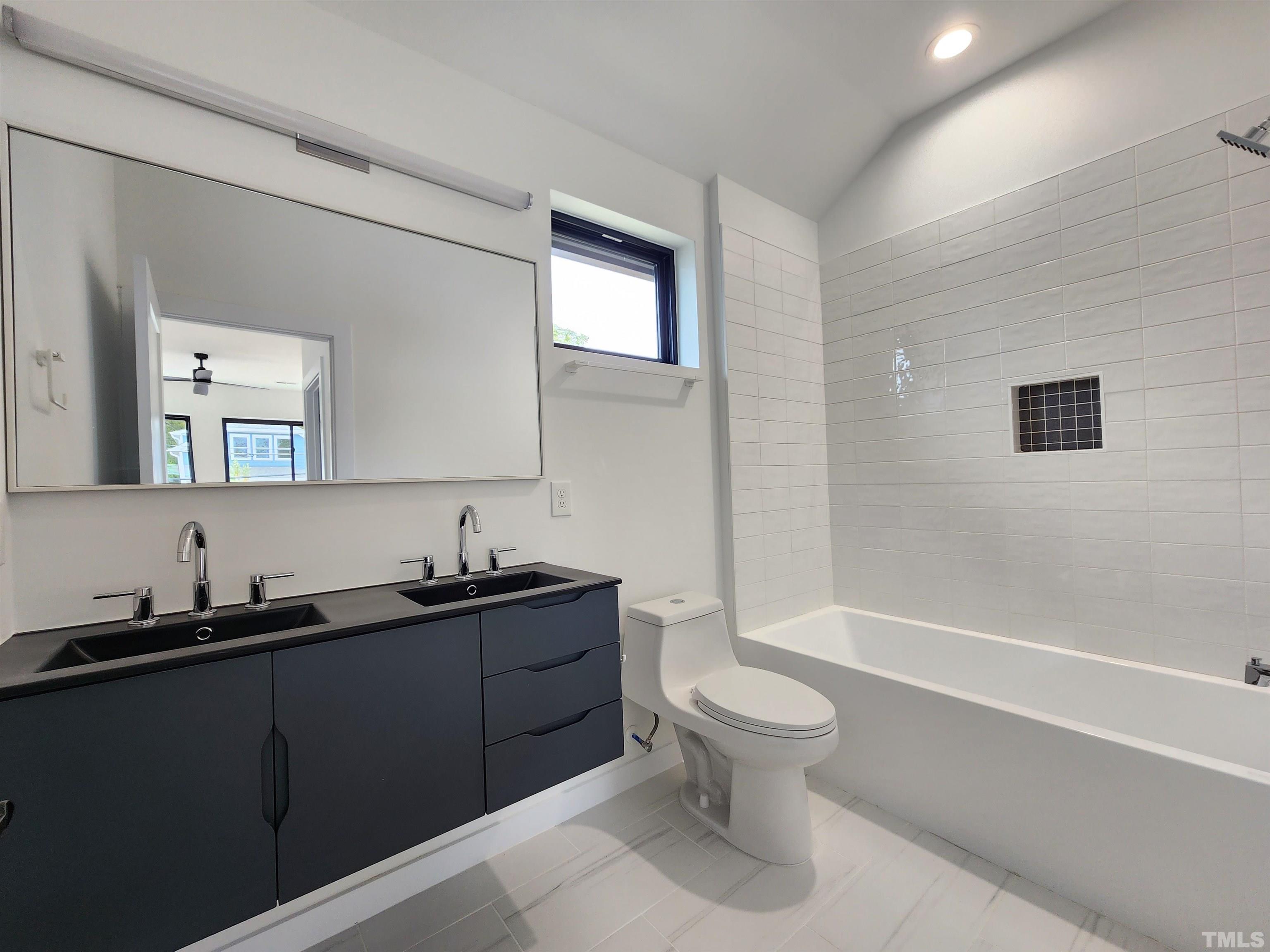 1203 East Lane Street Raleigh, NC 27601 - Photo 21 of 24 a bathroom with a granite countertop toilet a sink a mirror and bathtub