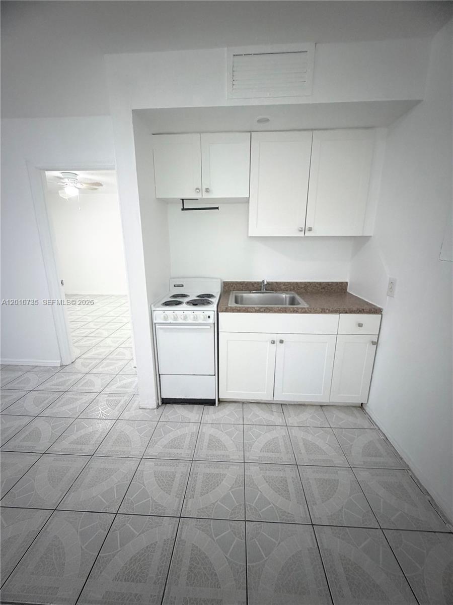 2736 Southwest 22nd Avenue, Unit 2 Miami, FL 33133 - Photo 6 of 12 a kitchen with a stove a sink and a refrigerator