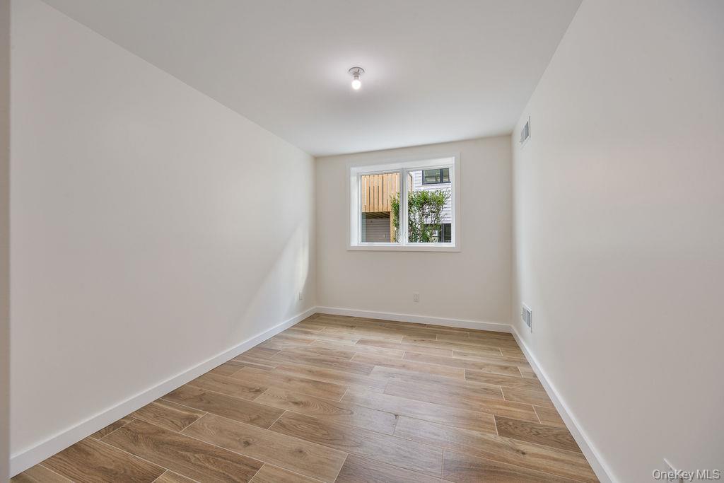 20 Singer Avenue, Unit 202 Spring Valley, NY 10977 - Photo 46 of 50 an empty room with wooden floor and windows