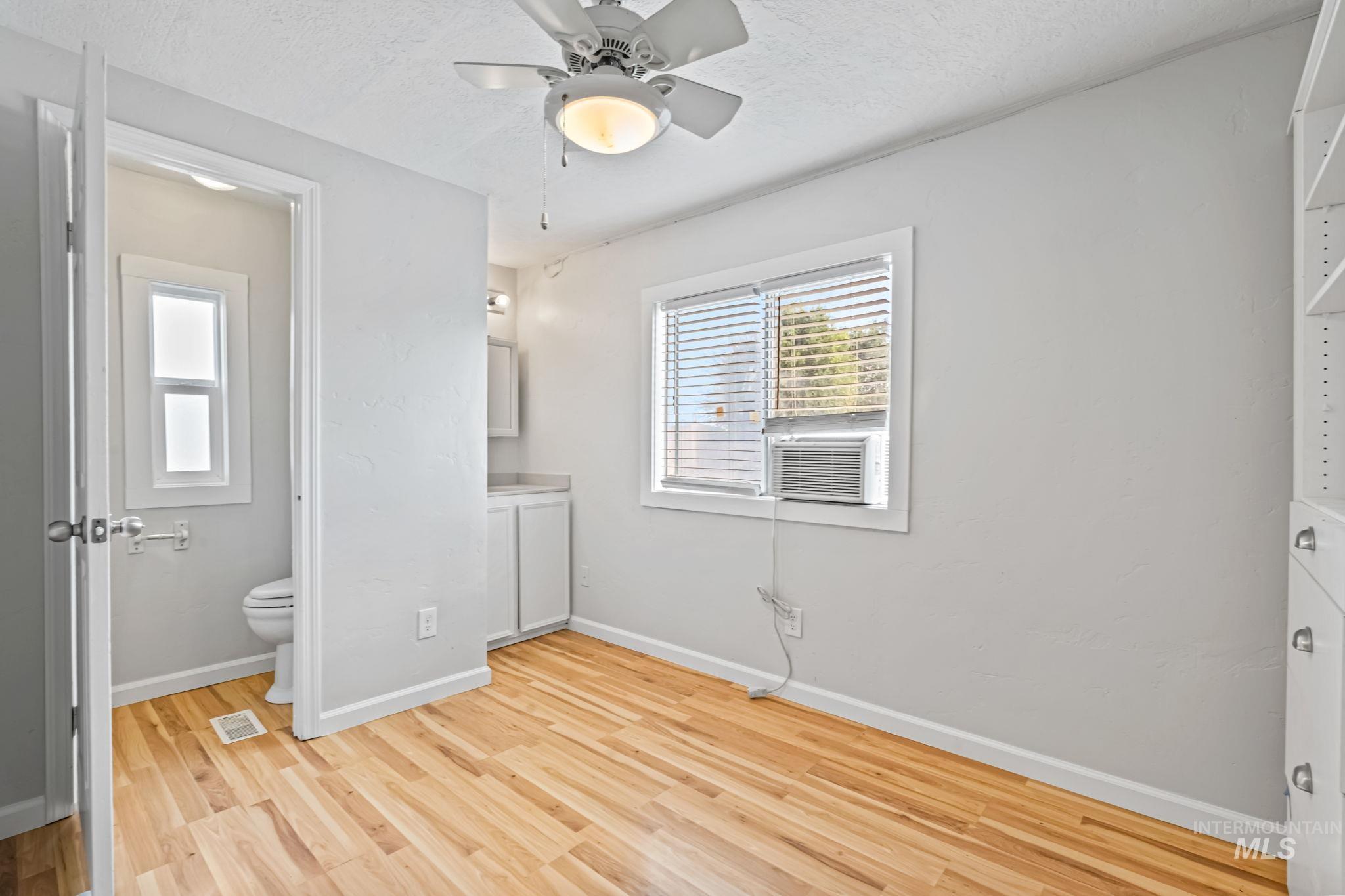 5015 East Ustick Road, Unit 181 Caldwell, ID 83605 - Photo 11 of 28 Unfurnished bedroom with light wood-type flooring, ceiling fan, ensuite bathroom, a textured ceiling, and cooling unit