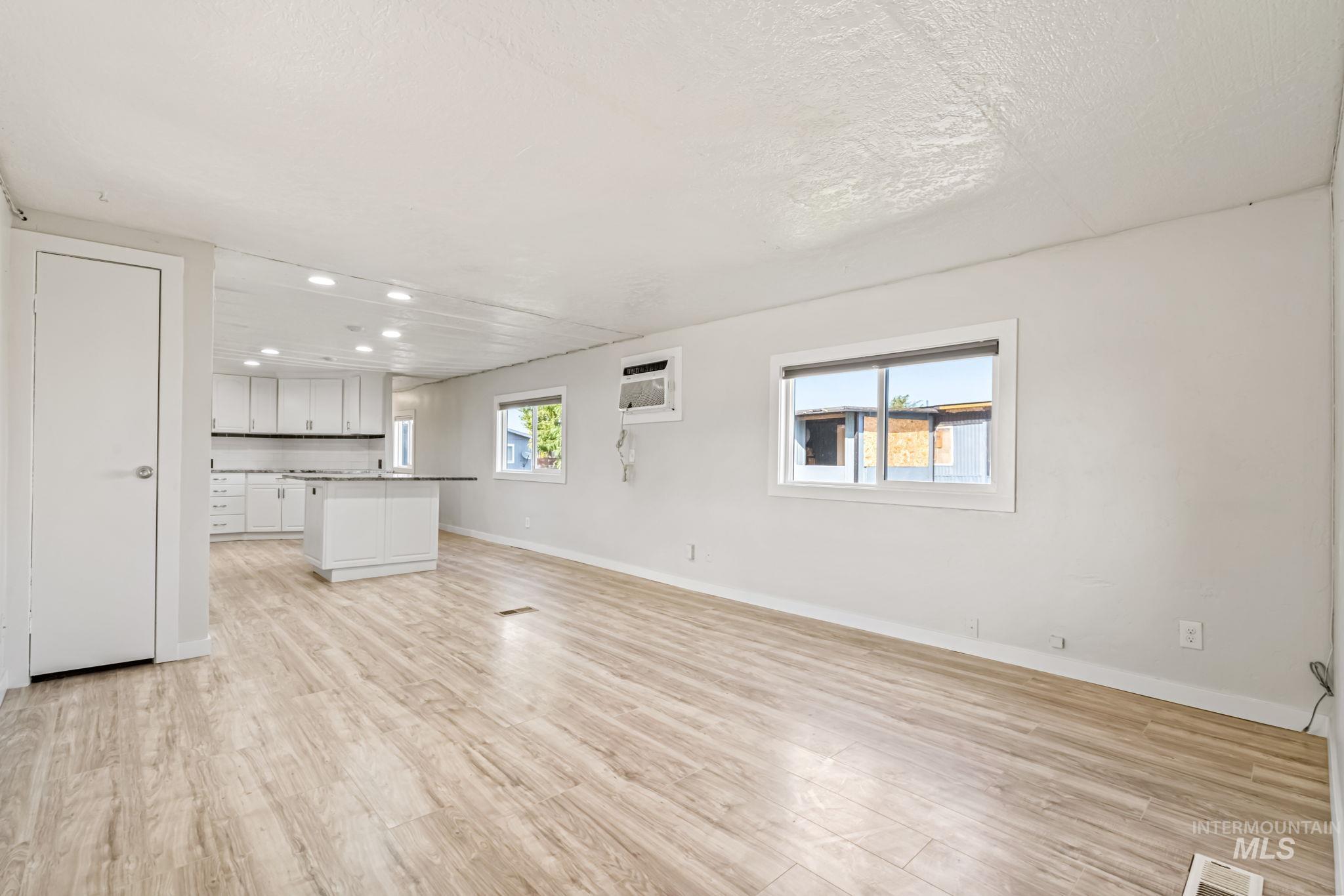 5015 East Ustick Road, Unit 181 Caldwell, ID 83605 - Photo 9 of 28 Unfurnished living room with light wood-style flooring, plenty of natural light, recessed lighting, and a wall unit AC