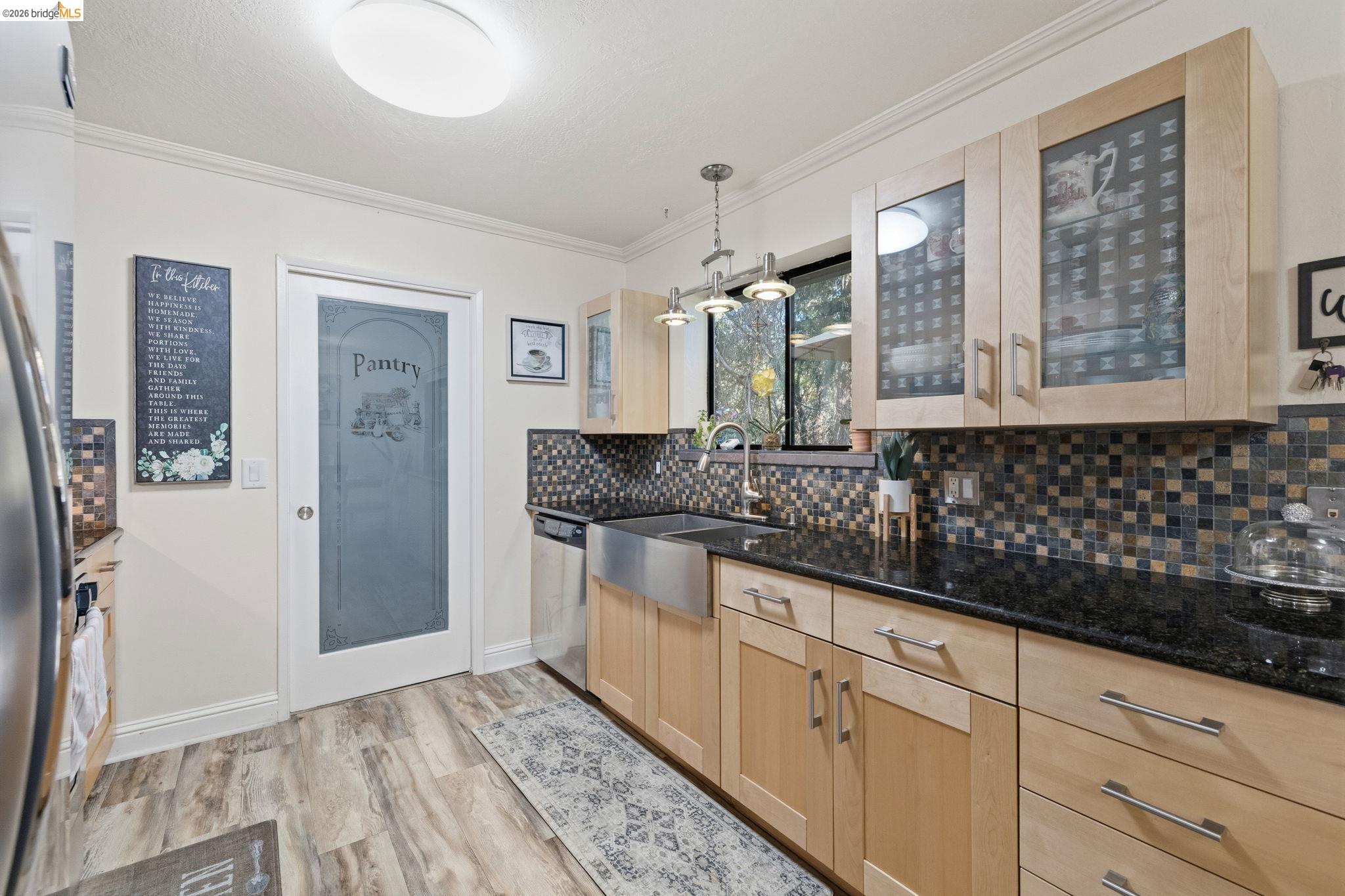 21999 Fallview Drive Sonora, CA 95370 - Photo 13 of 36 Kitchen with light wood finish cabinetry, dark stone counters, pendant lighting, crown molding, and light wood-style flooring