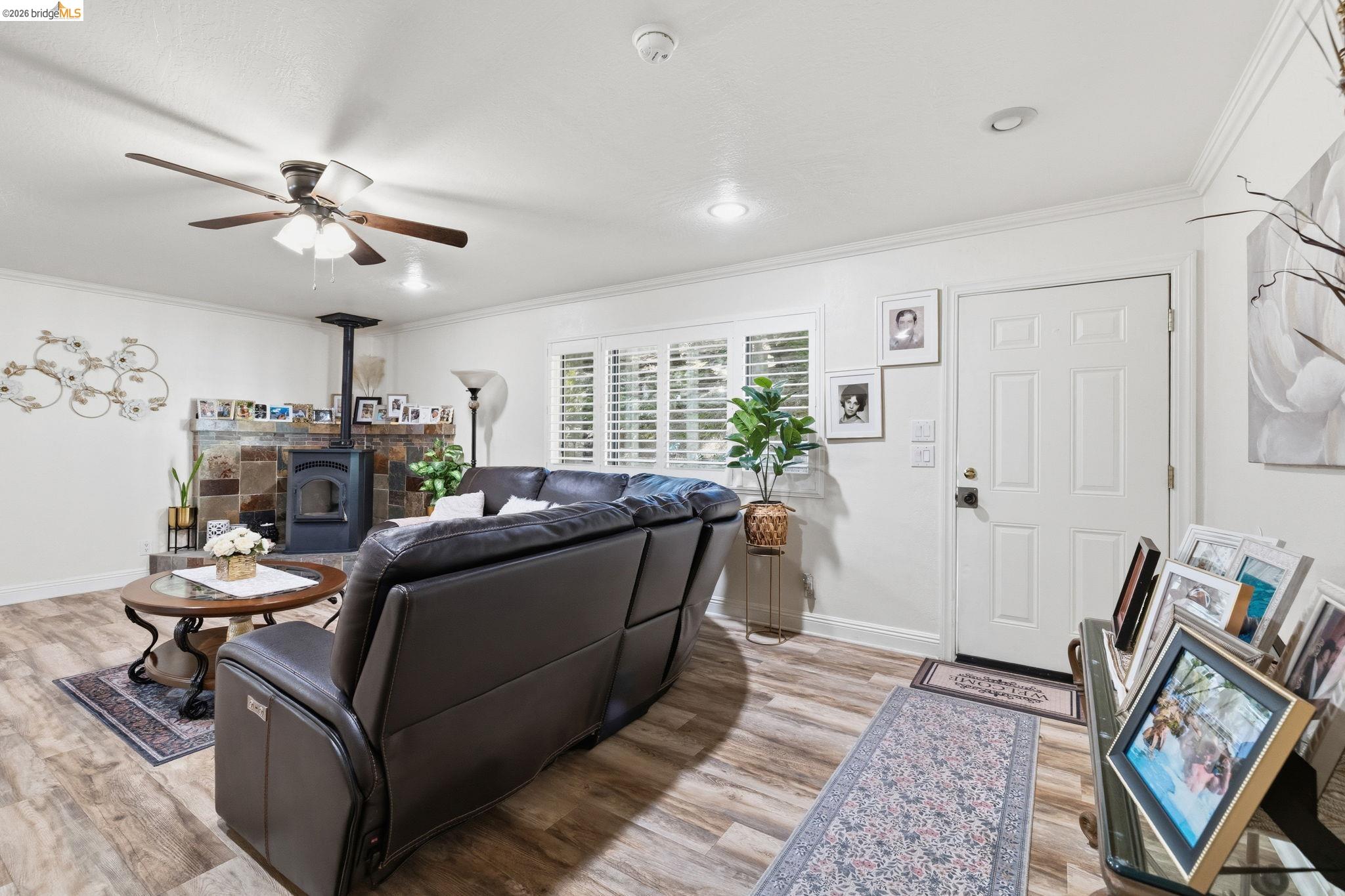 21999 Fallview Drive Sonora, CA 95370 - Photo 8 of 36 Living area with ornamental molding, ceiling fan, light wood-type flooring, and a wood stove