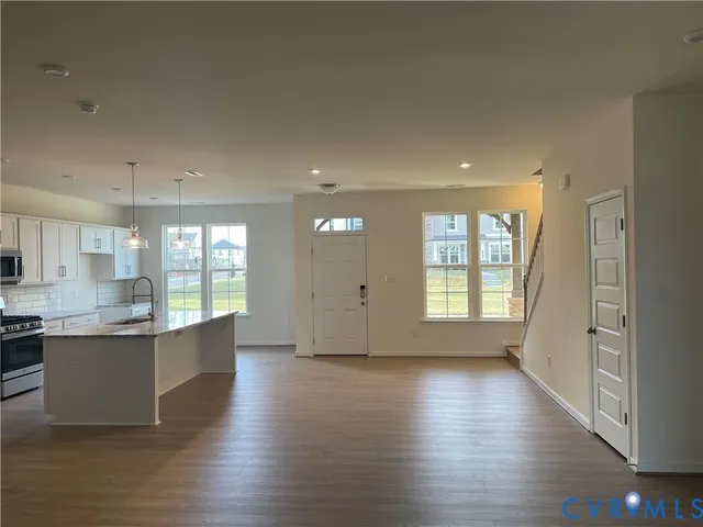 a large kitchen with stainless steel appliances granite countertop a large counter top a sink and a large window