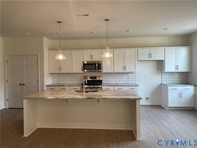 a kitchen with stainless steel appliances granite countertop a sink a stove and a granite counter tops with wooden floors