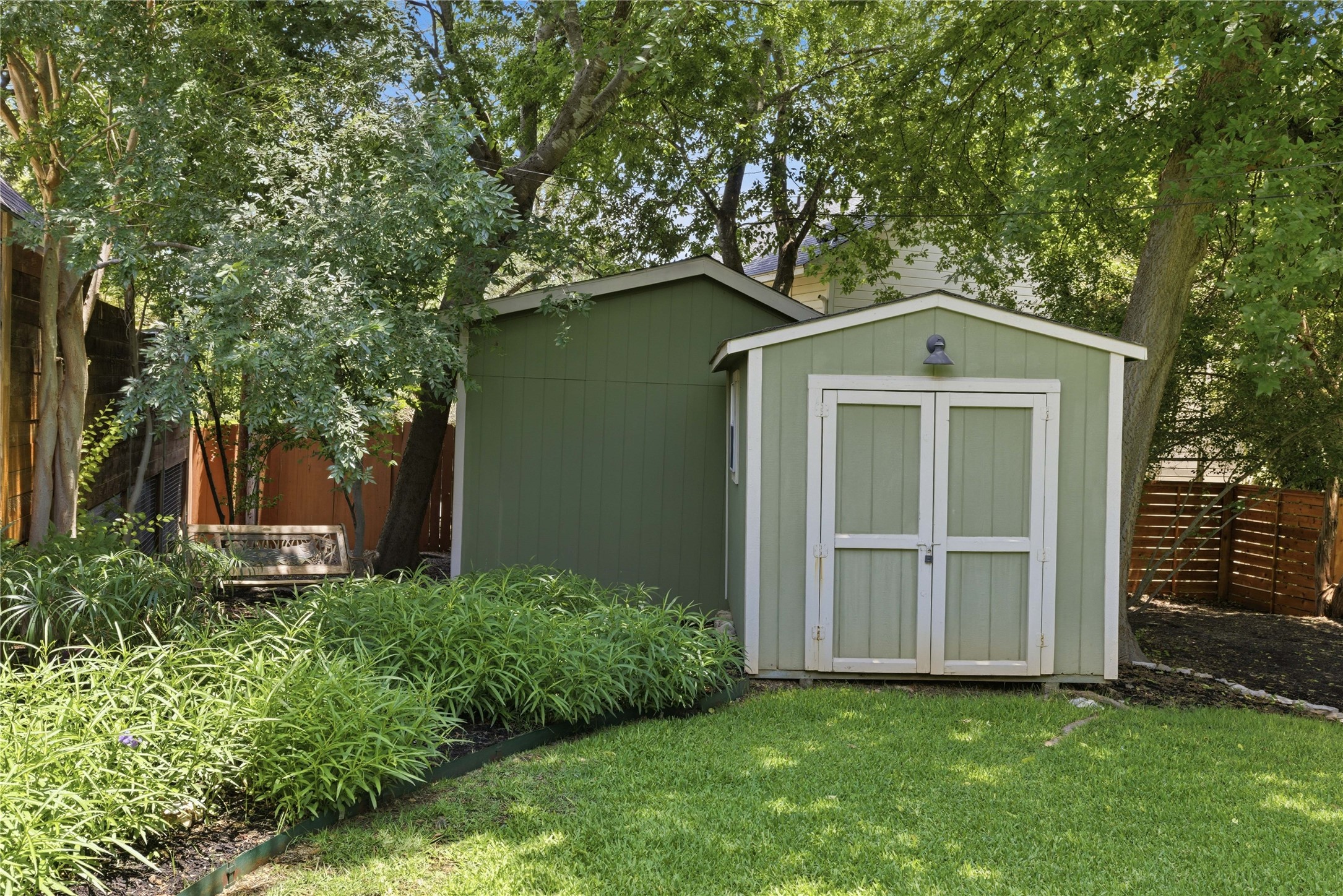 1204 Orlando Road Austin, TX 78733 - Photo 27 of 40 A verdant backyard retreat features two matching storage sheds nestled amidst mature trees.