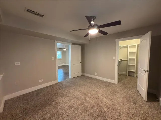 an empty room with closet and a ceiling fan