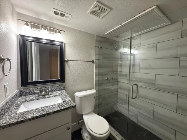 a bathroom with a granite countertop sink toilet and shower