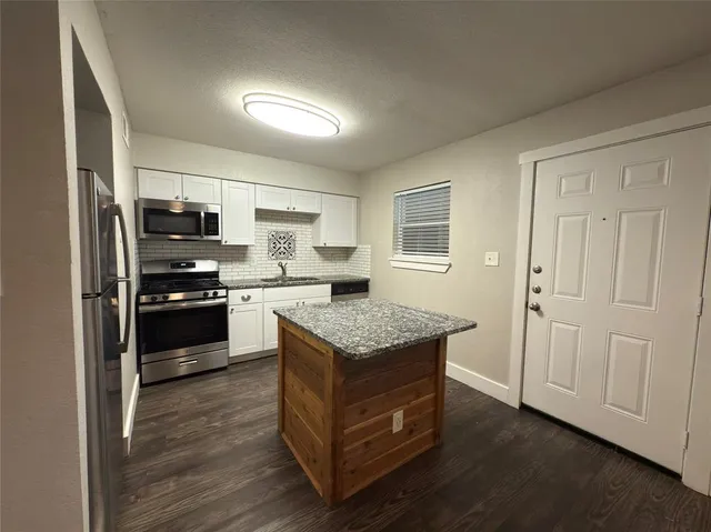 a kitchen with granite countertop a refrigerator and a stove top oven