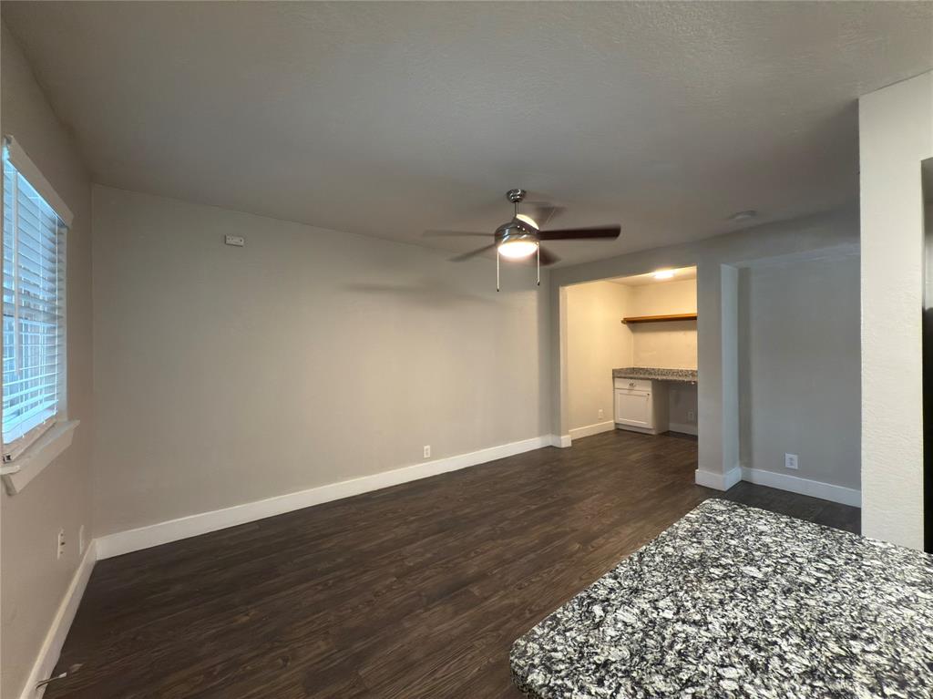 5928 Fletcher Avenue, Unit 16 Fort Worth, TX 76107 - Photo 9 of 20 an empty room with wooden floor cabinet and windows