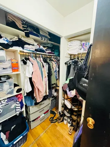 a view of walk in closet with clothes and shoes