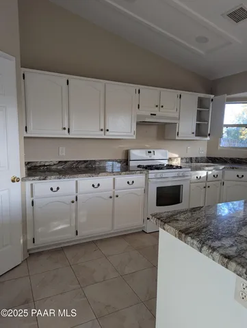 a kitchen with granite countertop a stove sink and cabinets