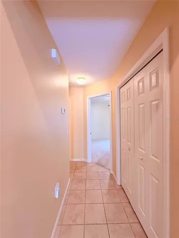 an empty room with a chandelier fan and windows