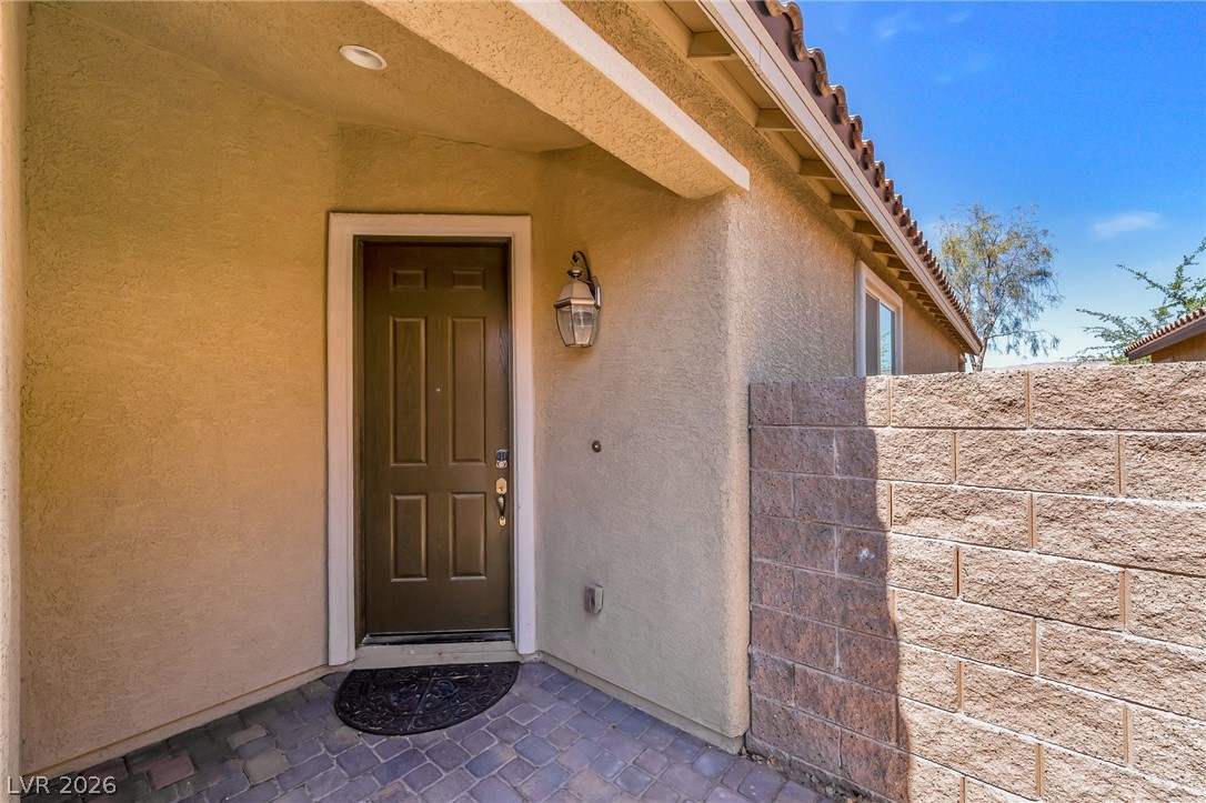 6245 Andover Wood Road Las Vegas, NV 89113 - Photo 4 of 37 A welcoming entry, with a robust brown door and an elegant wall lantern, complements the home's warm exterior.