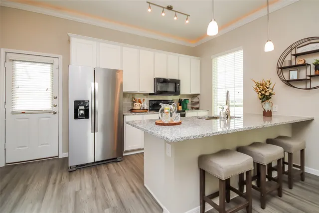 a kitchen with stainless steel appliances granite countertop a table chairs refrigerator and sink