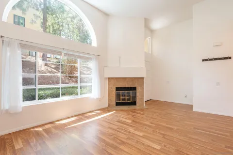 an empty room with wooden floor a fireplace and windows