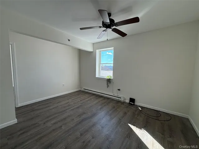 an empty room with wooden floor fan and windows